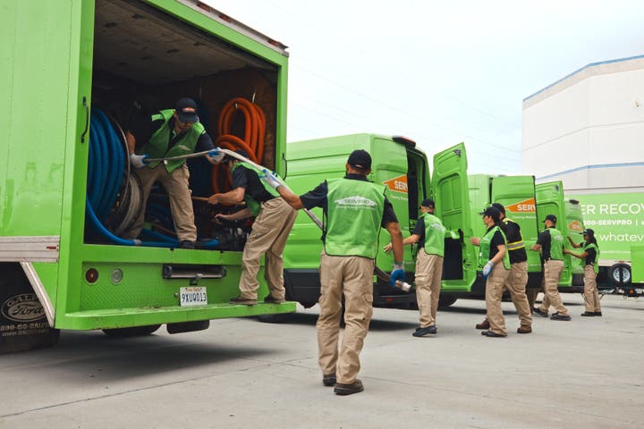 A row of SERVPRO vans and employees preparing to respond to a sewage emergency.